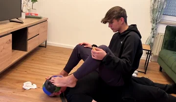 German master sitting on feet licking boy